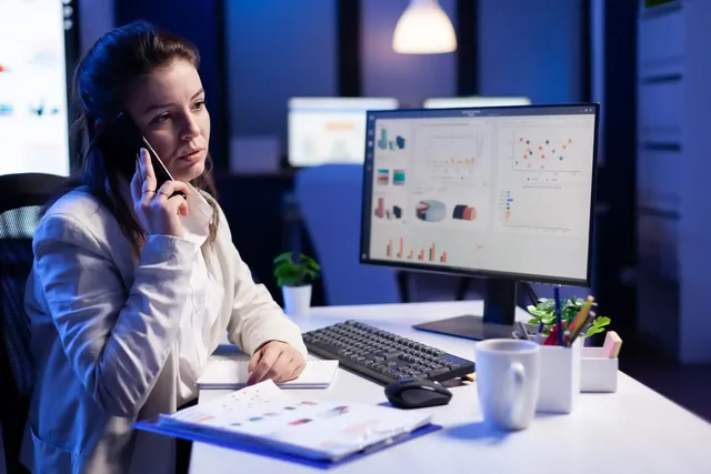 Analyst on a phone call in front of data dashboards